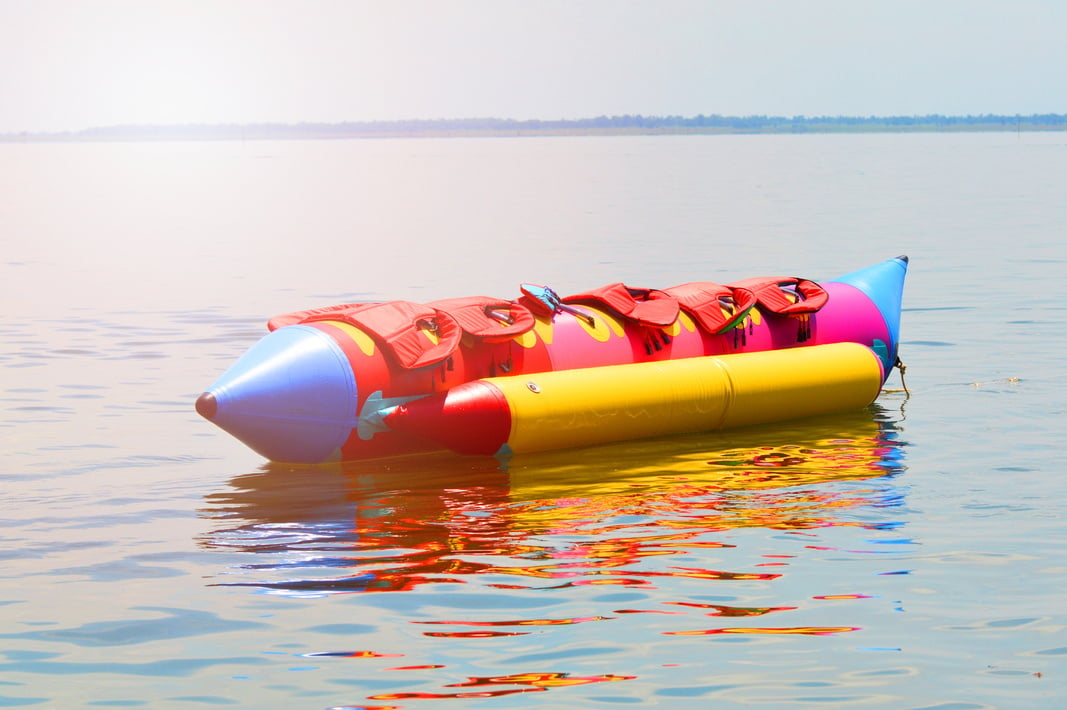 Banana Boat for fun / colorful of banana boat float on water surface in summer day - banana boat with life jacket on banana boat at the sea